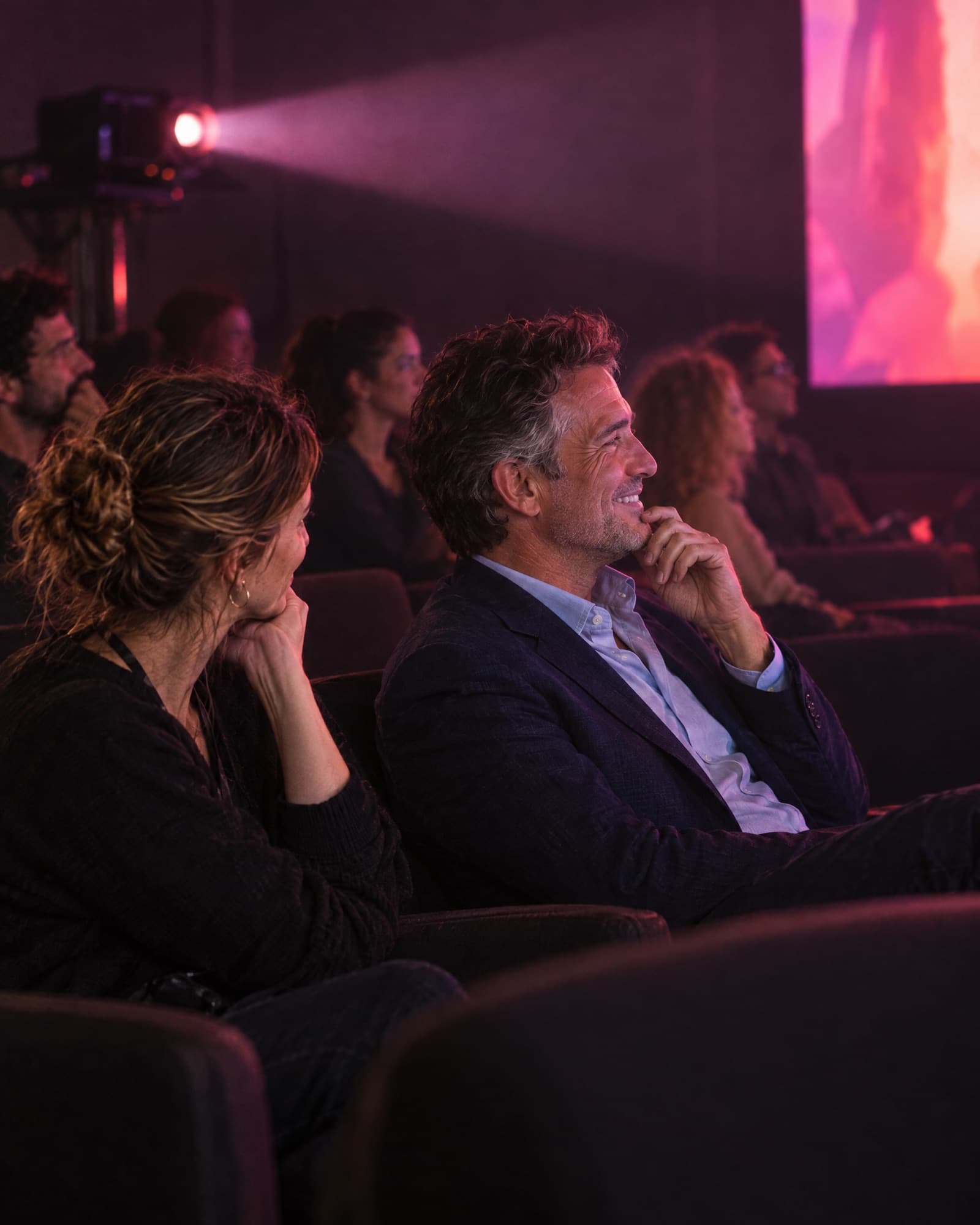 The director and the client watch the finished film on the big screen of a screening room.